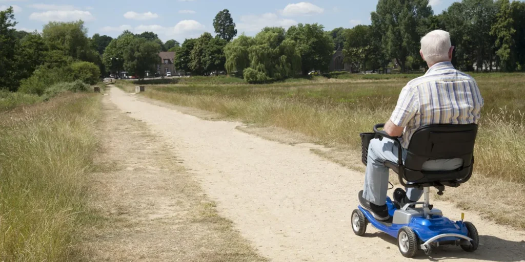 man riding a mobility scooter on a path through fields